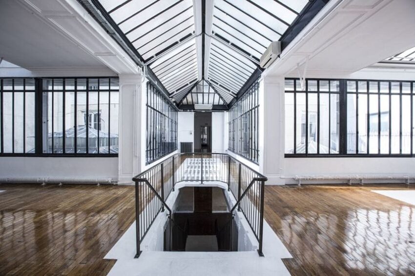Spacious industrial-style loft with glass ceiling, large windows, and wooden floors.