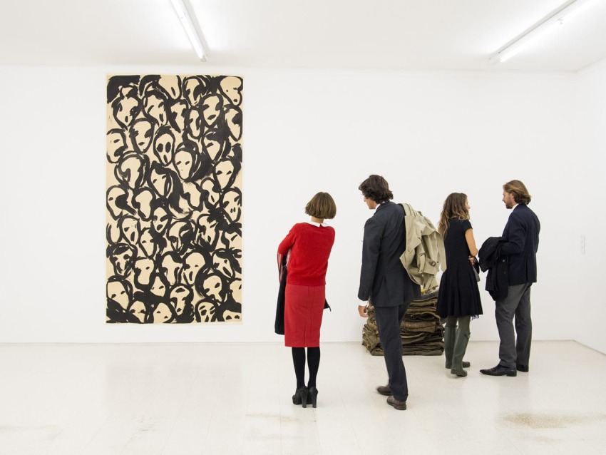 People viewing abstract black and beige art piece in a modern gallery setting.