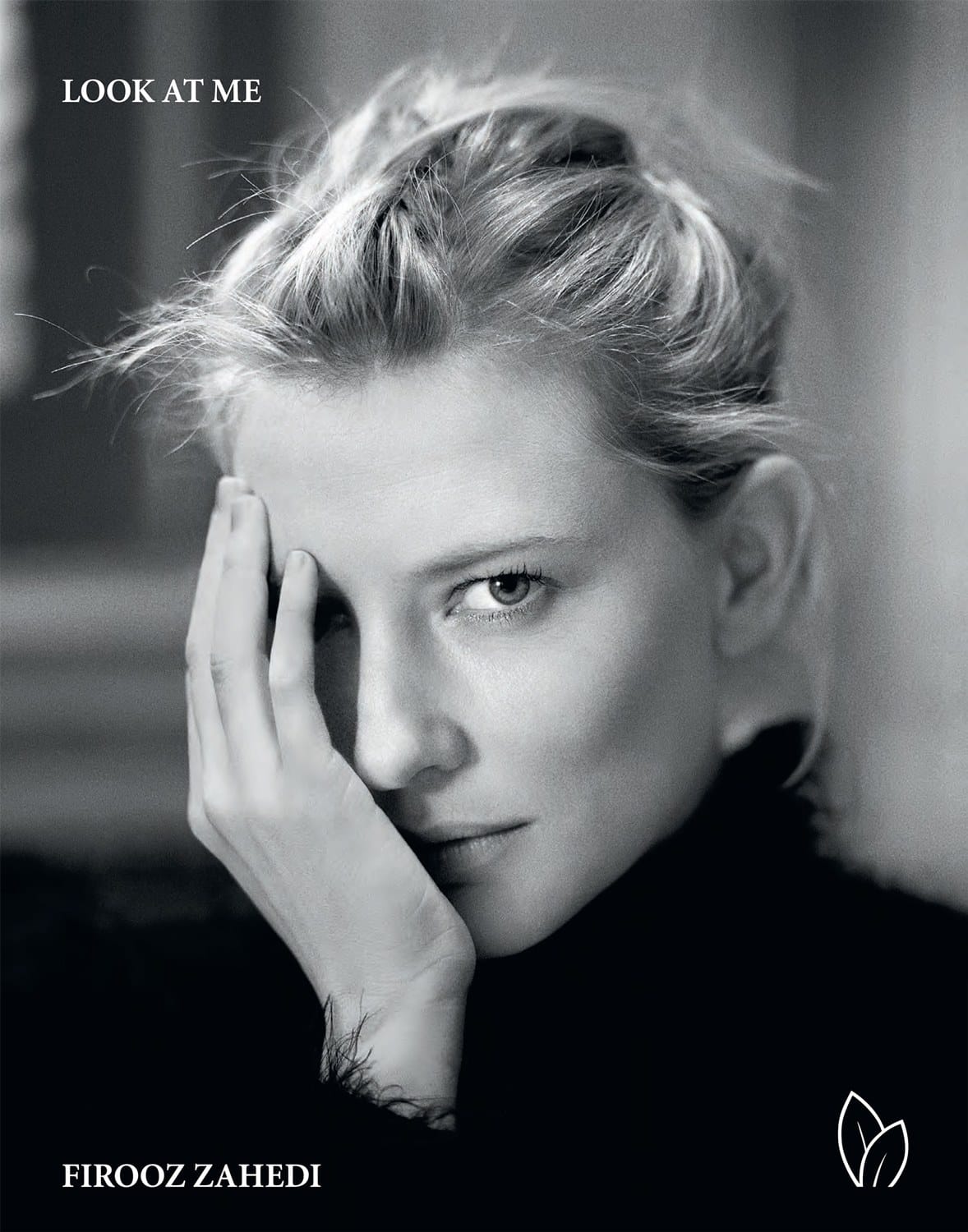 Black and white portrait of a person with blonde hair, partially covering their face with hand, looking directly at camera.