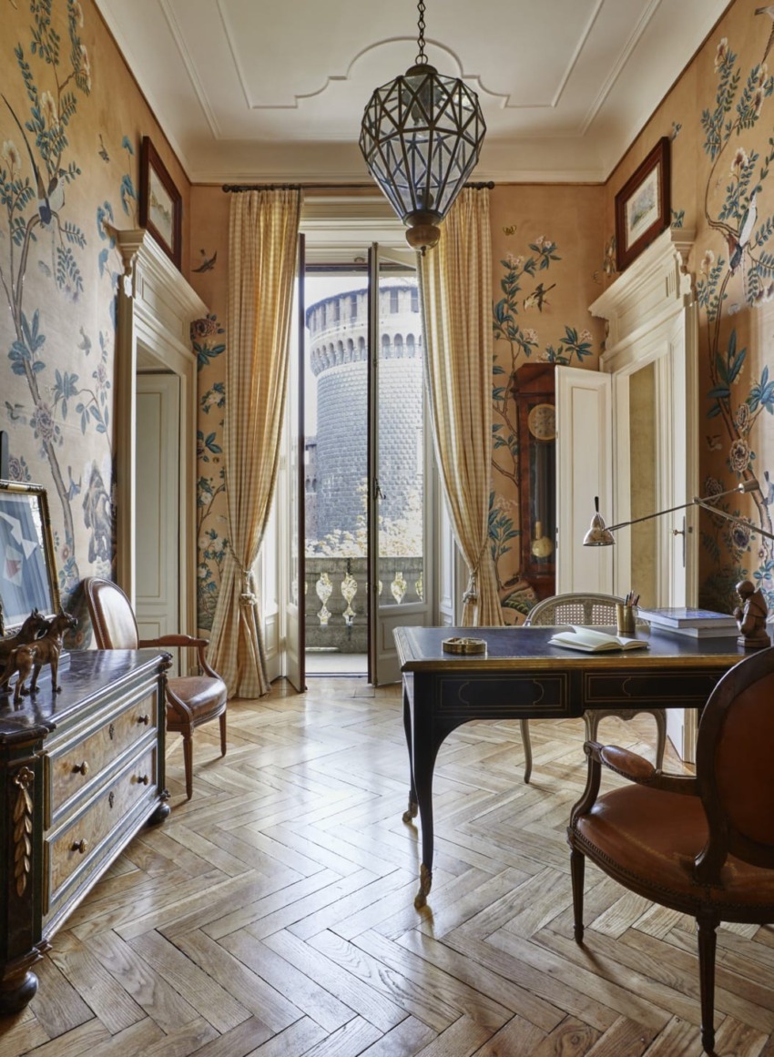 Elegant home office with vintage wooden furniture, ornate wallpaper, and a window view of a castle turret outside.