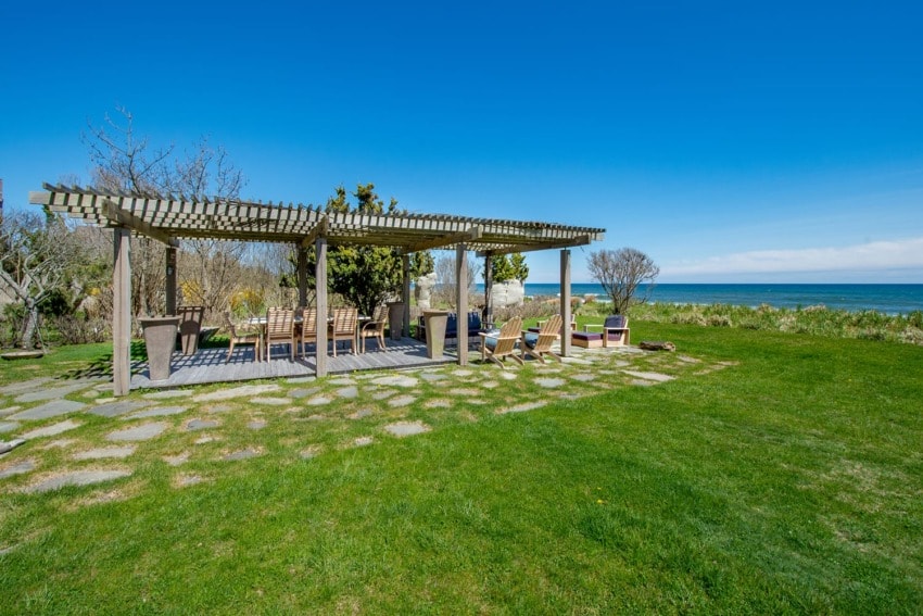 Pergola with seating on a grassy lawn overlooking the ocean under a clear blue sky