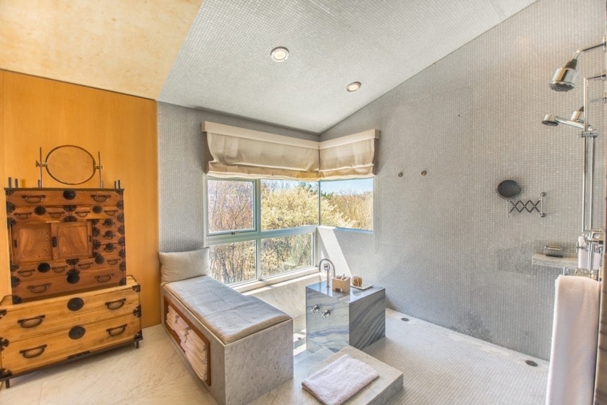 Luxurious bathroom with large windows, wooden accents, modern decor, and a spacious walk-in shower.