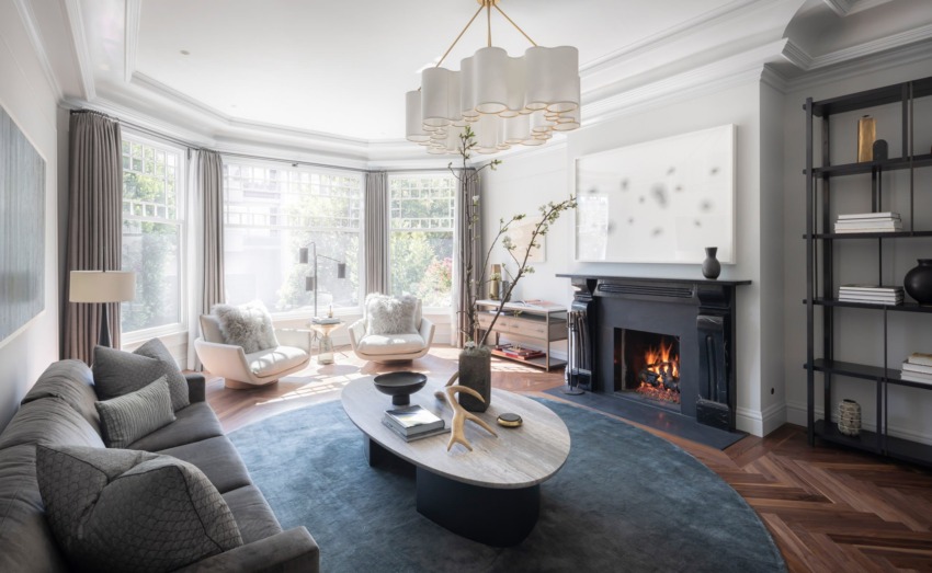 Luxurious modern living room with large windows, elegant furniture, a cozy fireplace, and stylish decor elements.