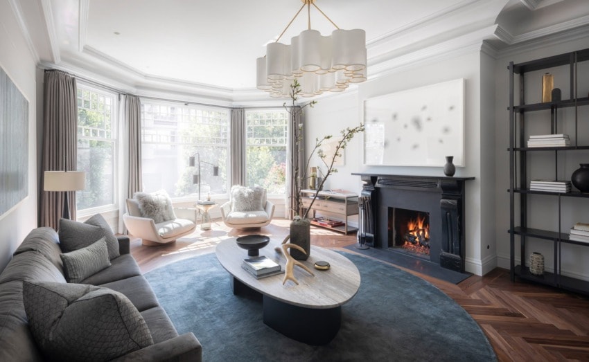 Luxurious modern living room with large windows, elegant furniture, a cozy fireplace, and stylish decor elements.