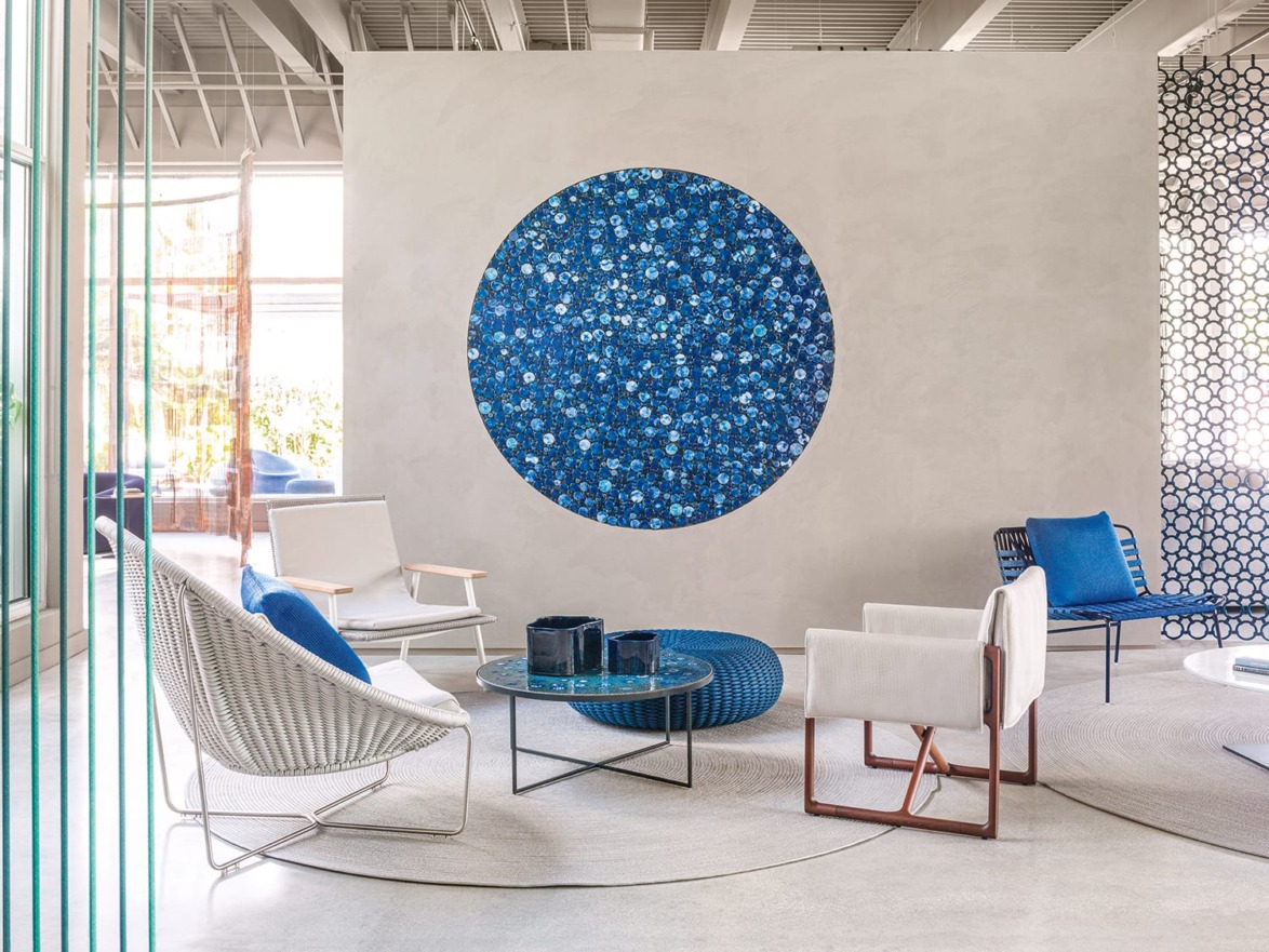 Modern lounge area with white and blue chairs, a central circular rug, and a large blue circular wall art piece.