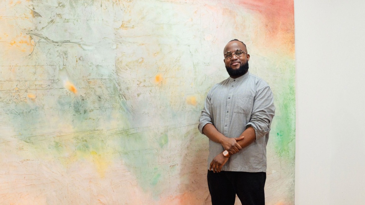Portrait of the artist Kemar Keanu Wynter with one of his paintings.