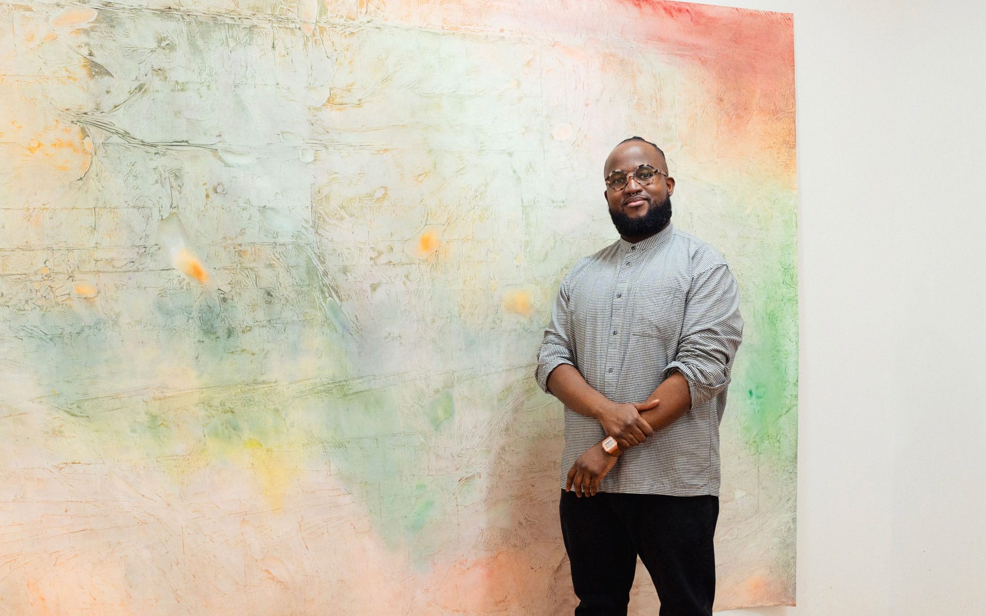 Portrait of the artist Kemar Keanu Wynter with one of his paintings.