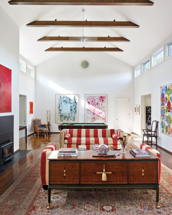 Spacious living room with modern art, striped sofa, wooden ceiling beams, and a mix of contemporary and vintage decor.