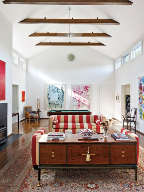Spacious living room with modern art, striped sofa, wooden ceiling beams, and a mix of contemporary and vintage decor.