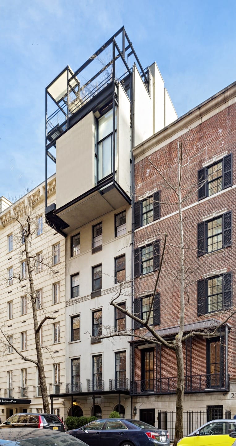 Modern building facade with striking geometric structure, featuring large windows and a blend of brick and concrete.