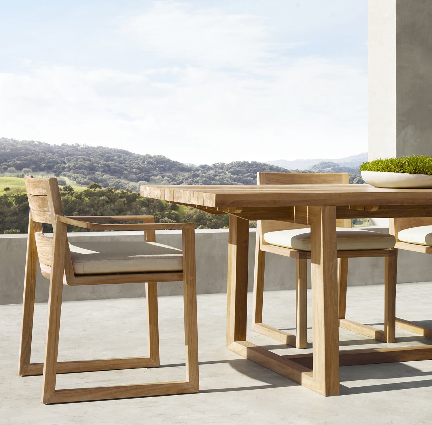 Outdoor wooden dining set on a patio with scenic mountain view in the background.
