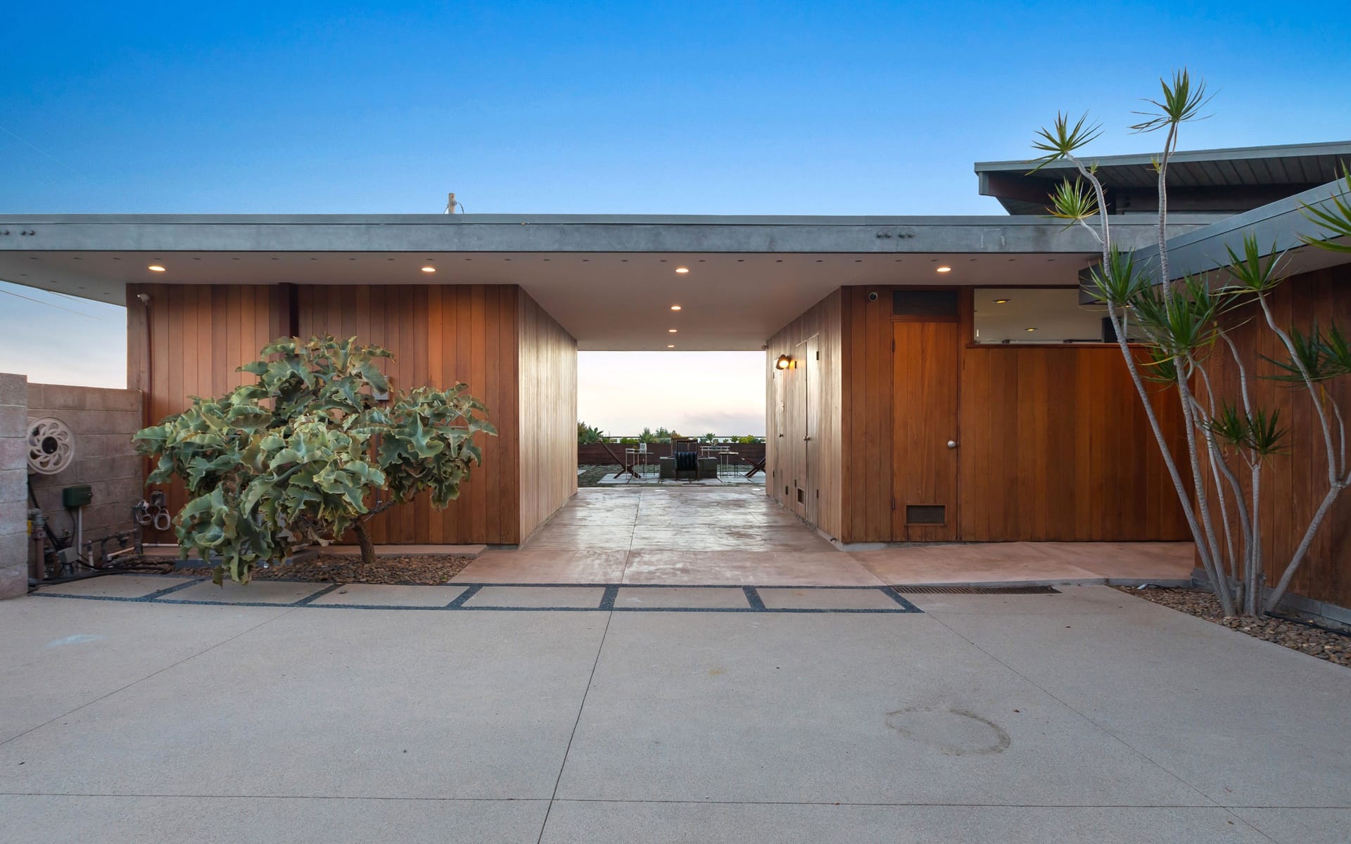 Modern house exterior with wooden panels, large windows, and minimalist design under a clear blue sky.