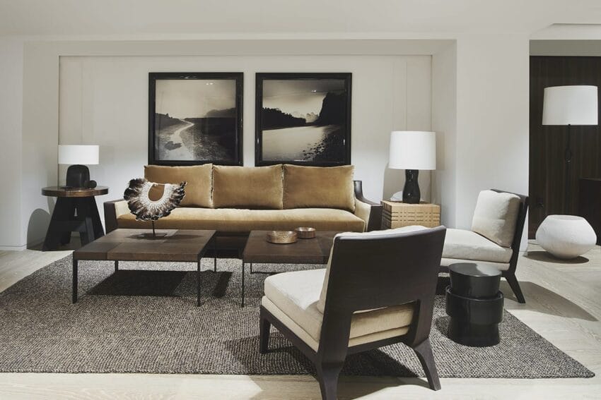 Modern living room with a brown sofa, two framed photos, a wooden coffee table, and chairs on a textured rug.