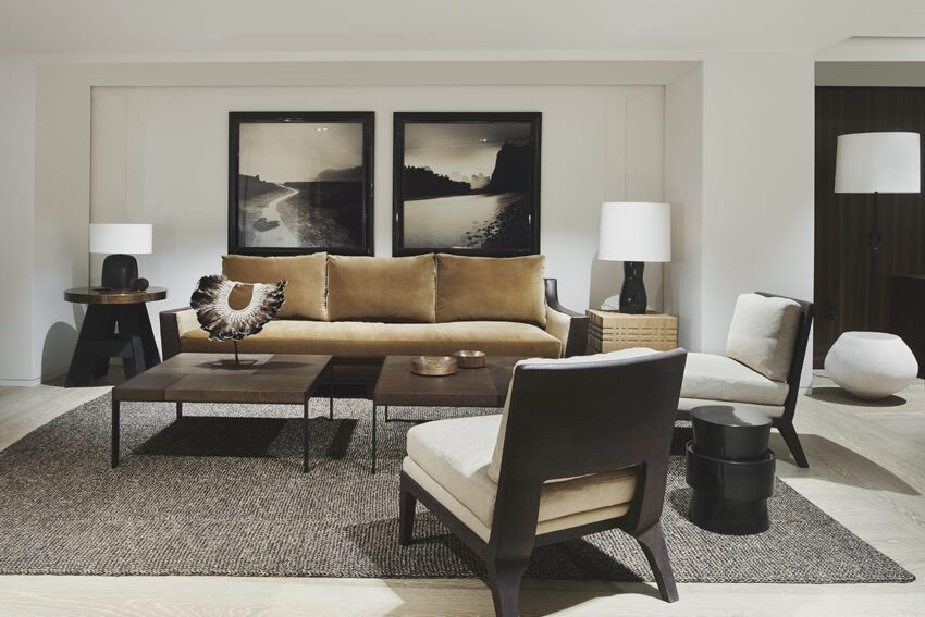 Modern living room with a brown sofa, two framed photos, a wooden coffee table, and chairs on a textured rug.