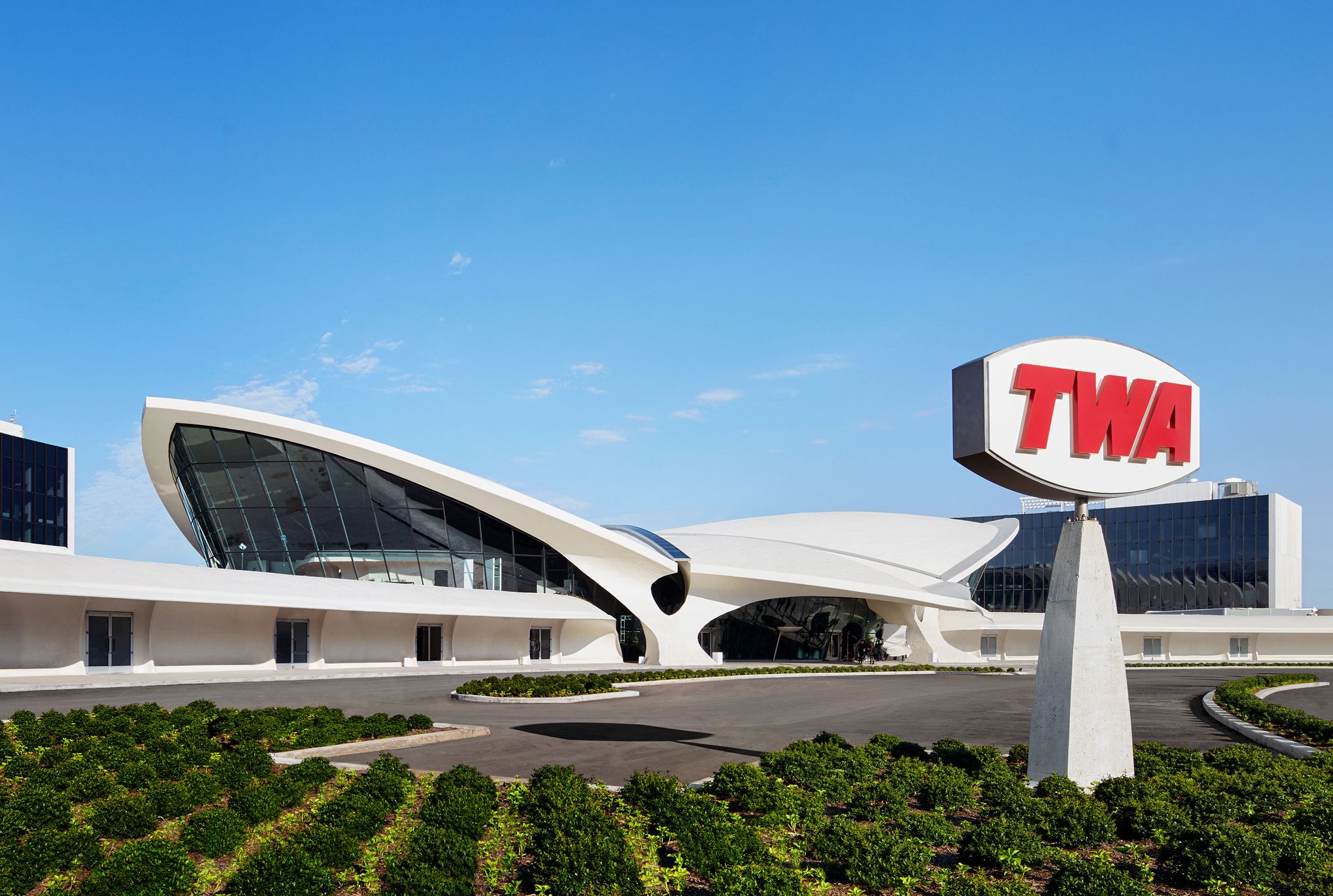 Exterior view of the TWA Flight Center with its iconic mid-century modern architecture and prominent TWA sign at JFK Airport.
