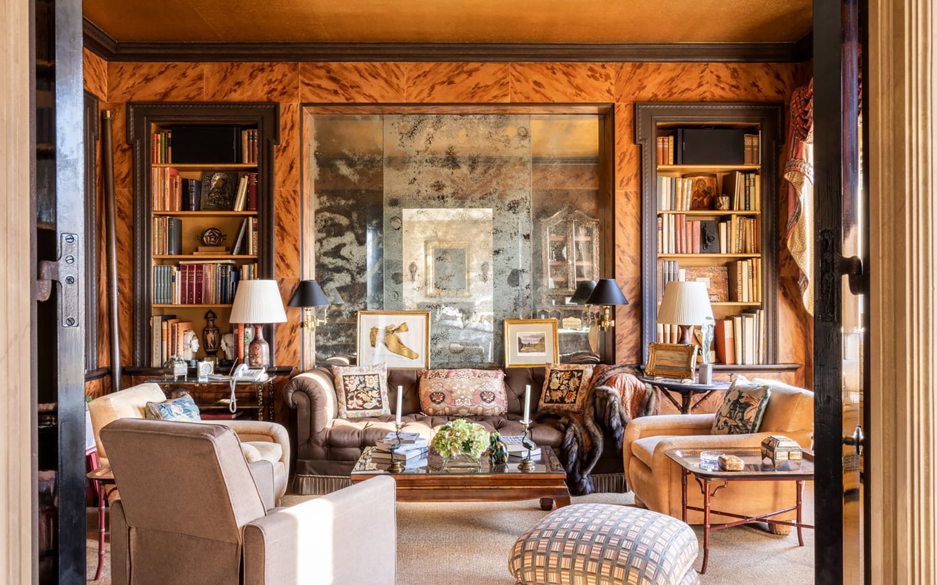 Cozy living room with plush seating, bookshelves, artwork, and decorative lamps on a wooden coffee table.