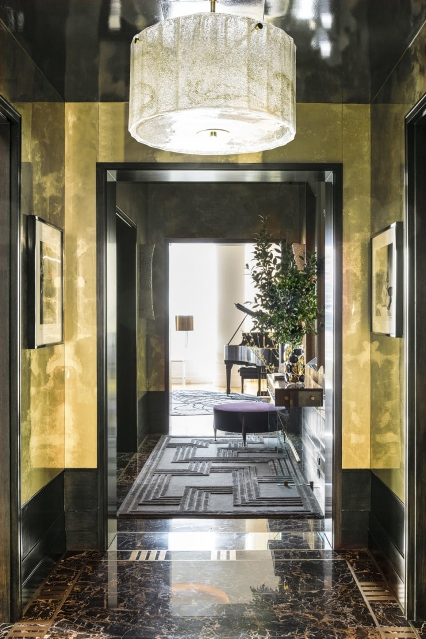 Luxurious hallway with marble floor, elegant chandelier, contemporary decor, and a glimpse of a piano in the adjacent room.