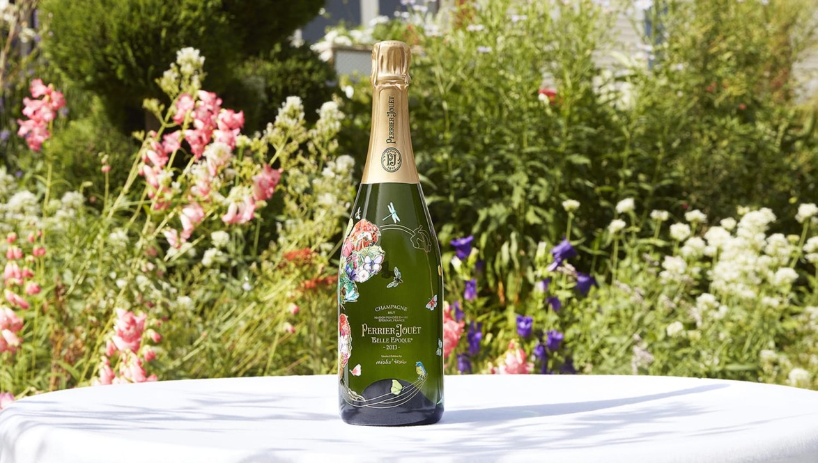 Bottle of champagne on a table with a floral garden background