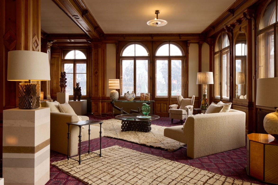 Elegant living room with wooden paneling, large windows, cozy sofas, coffee table, decorative lamps, and a plush rug.