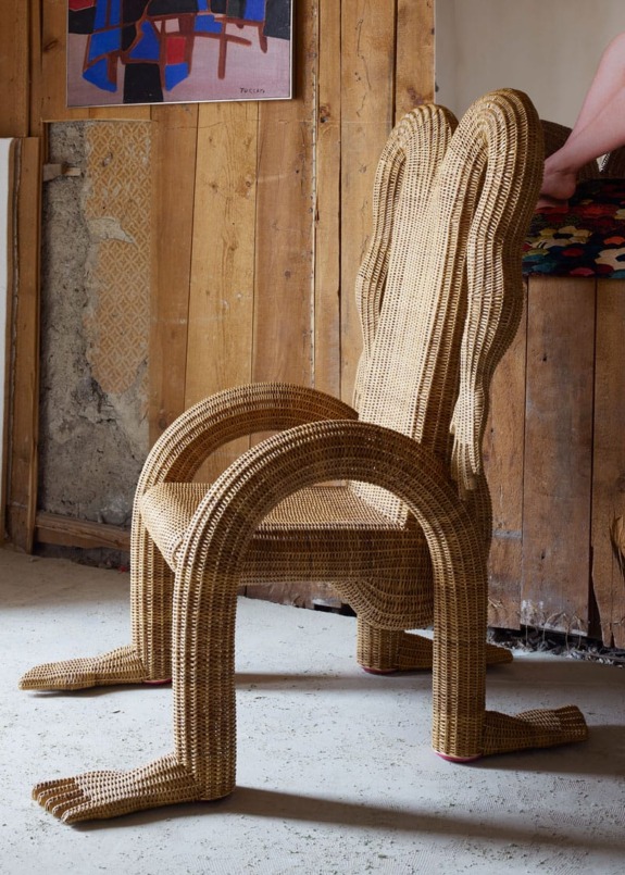 Unique wicker chair with a playful design resembling a creature, placed in a rustic interior setting.