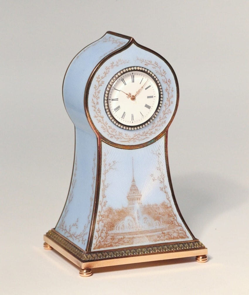 ornate blue clock with landscape imagery and gold accents on a light background