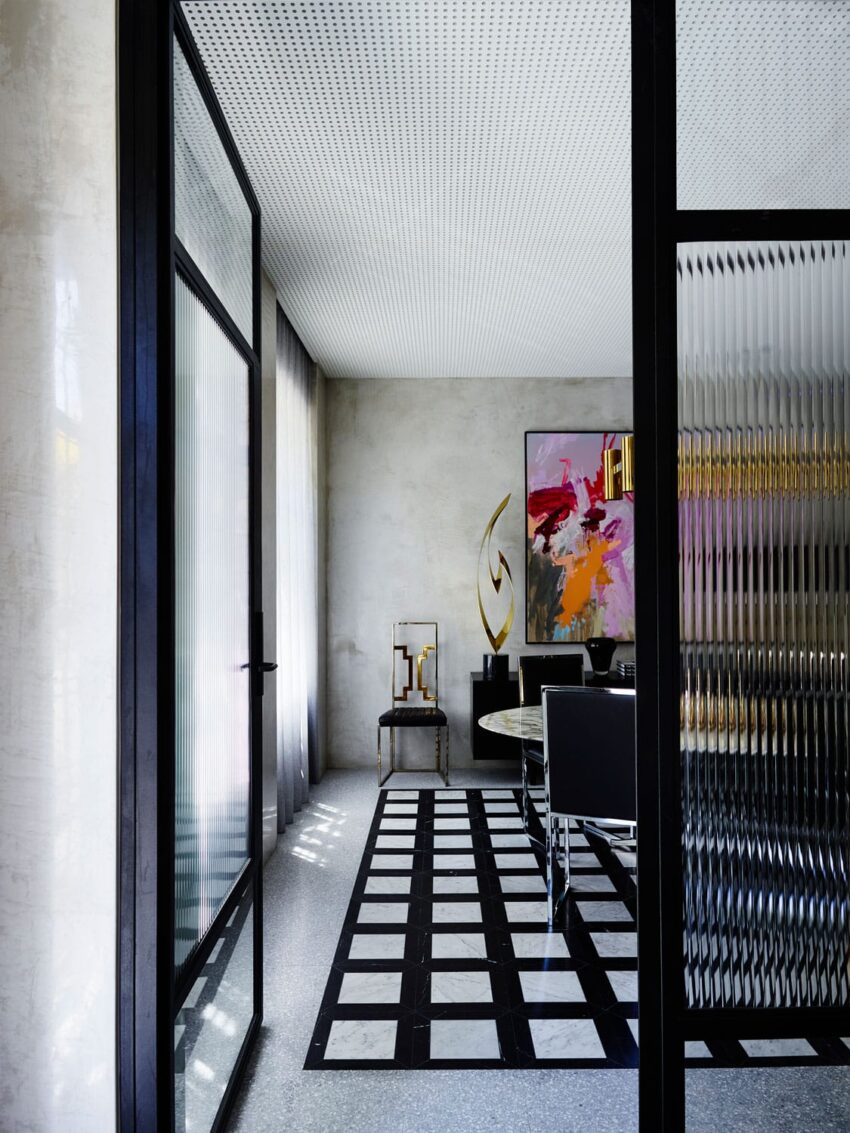 Modern dining room with geometric black and white floor, glass doors, and abstract painting on concrete walls