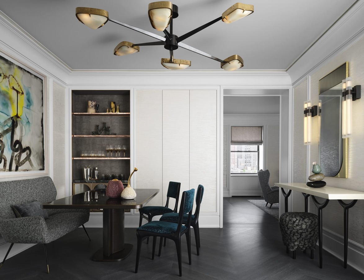 Modern dining room with dark table, upholstered chairs, abstract art, unique ceiling light fixture, and wall-mounted lights.