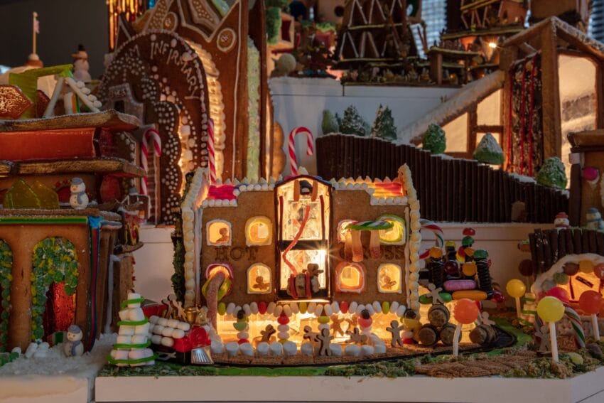A display of decorative gingerbread houses with intricate designs, candy details, and festive holiday themes.