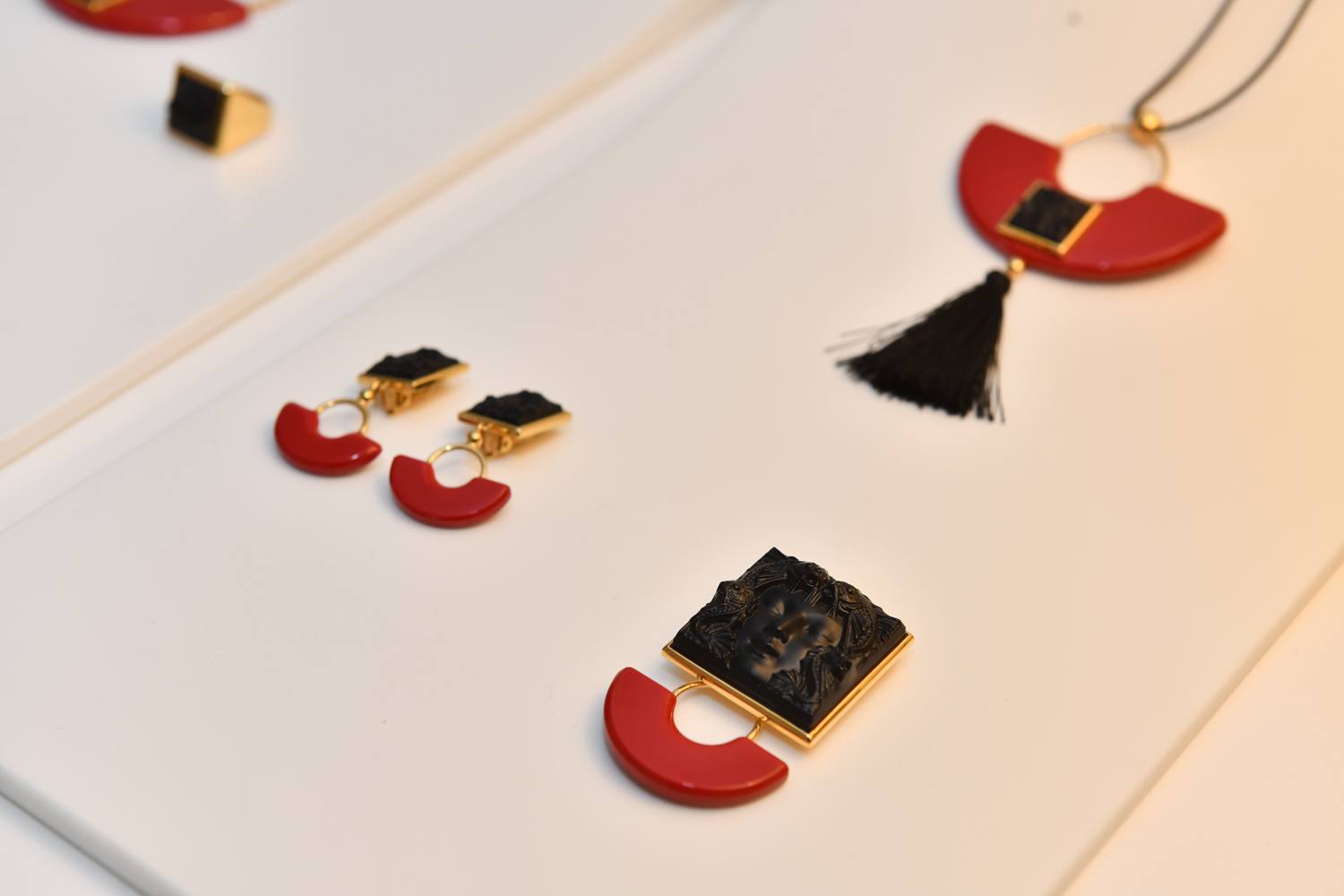 Red and black jewelry set with earrings, pendant necklace, and brooch featuring geometric shapes on a white background.