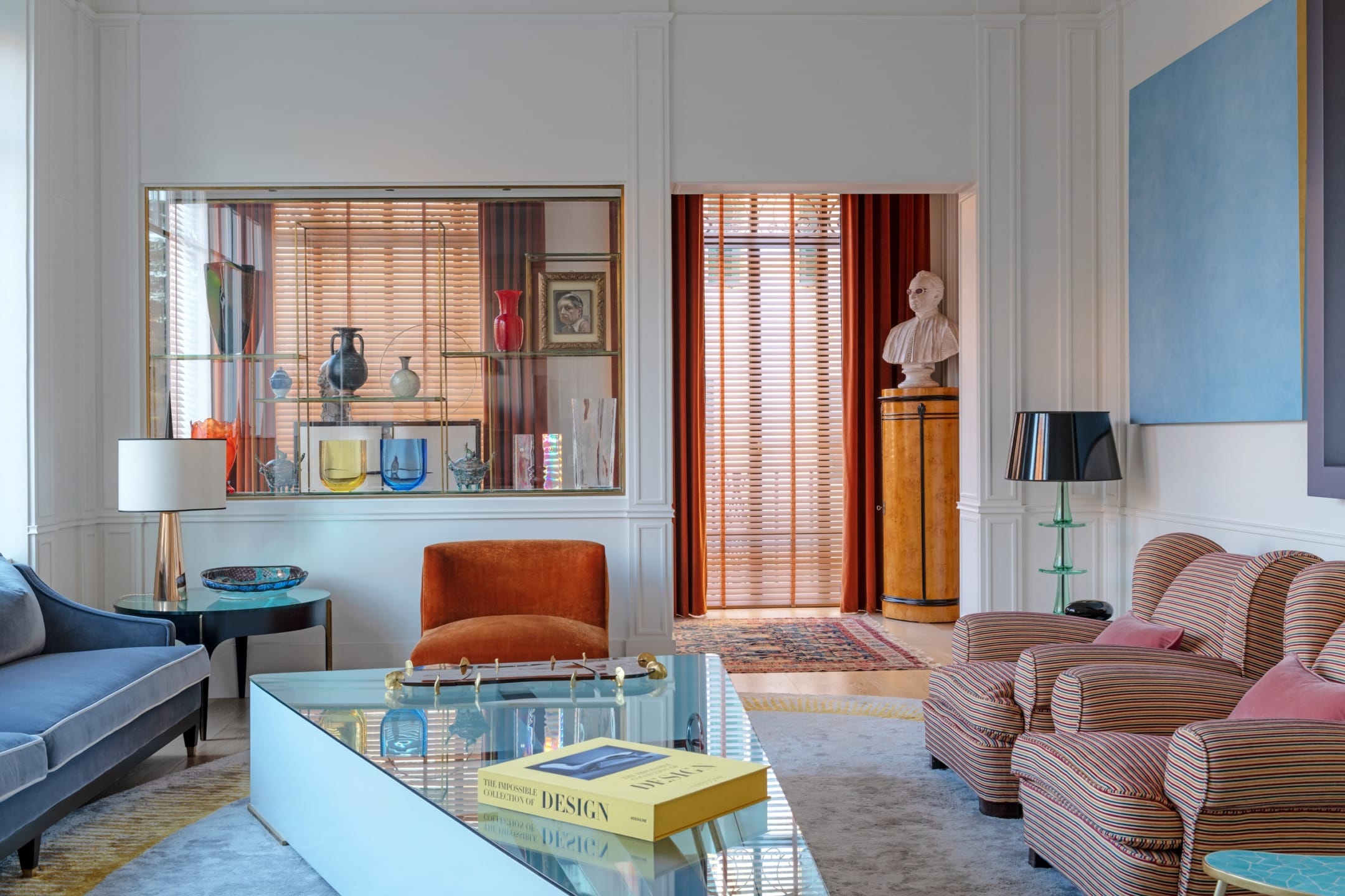 Luxury living room with modern furniture, colorful decor, large window, and bookshelf, creating an inviting and stylish atmosphere.