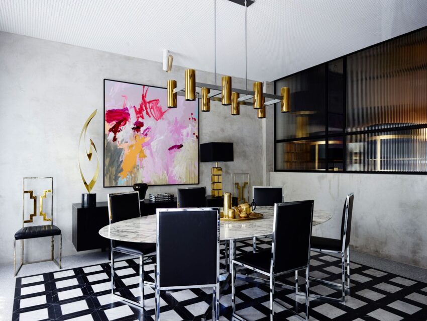Modern dining room with black chairs, marble table, abstract art, and gold accents.