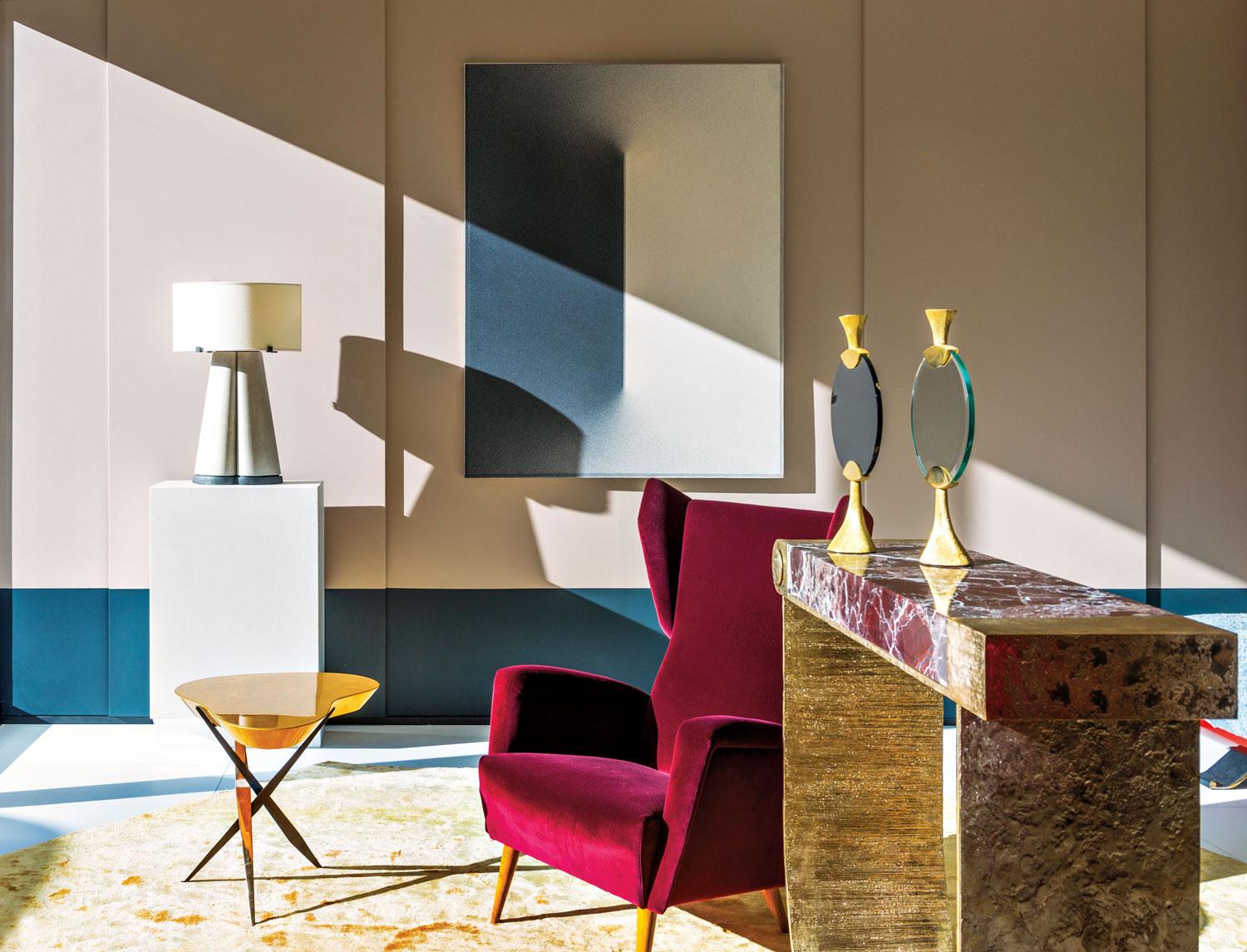 Stylish interior featuring a burgundy armchair, elegant table with gold accents, lamp, and modern artwork on the wall.