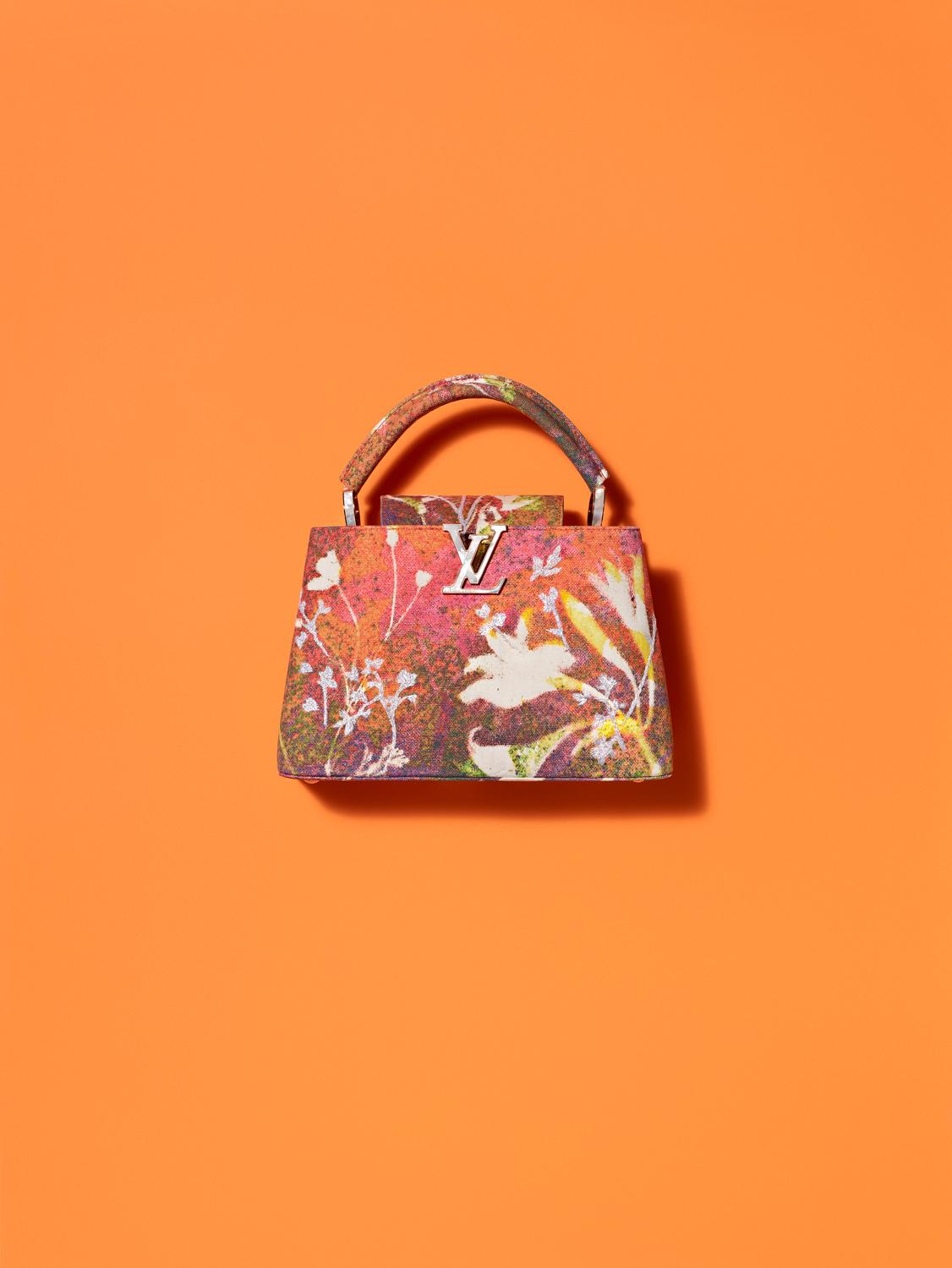 Colorful designer handbag with floral pattern on an orange background.