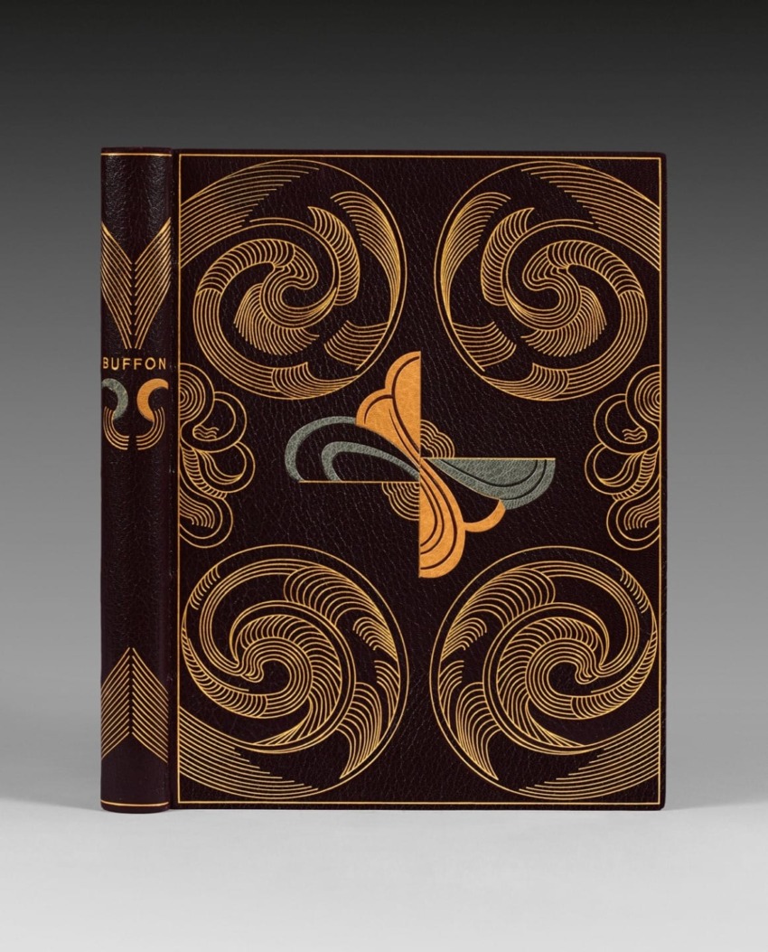 Leather-bound book with intricate swirling patterns and geometric designs in gold and silver on a dark cover.