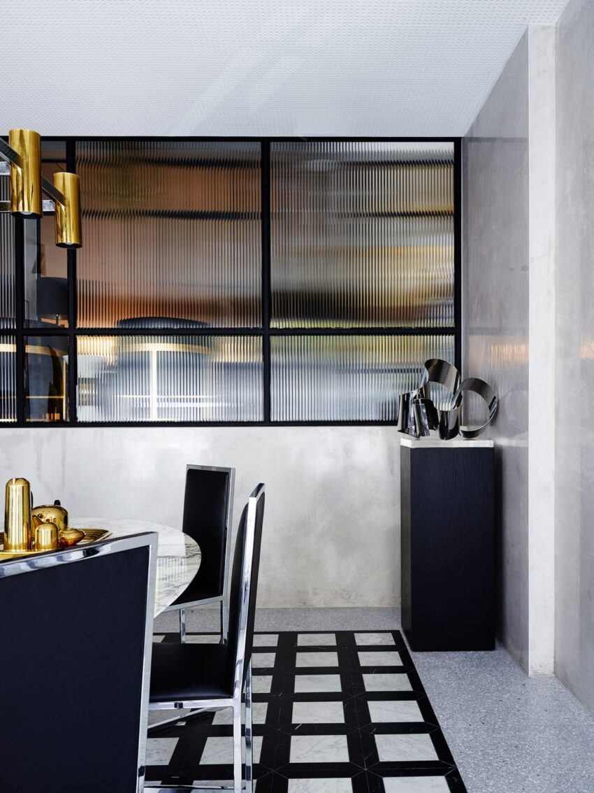 Modern dining room with black and white checkered floor, glass table, black chairs, and gold decorative accents.