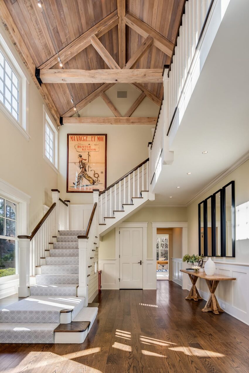 Spacious foyer with wooden ceiling, elegant staircase, and large windows allowing abundant natural light.
