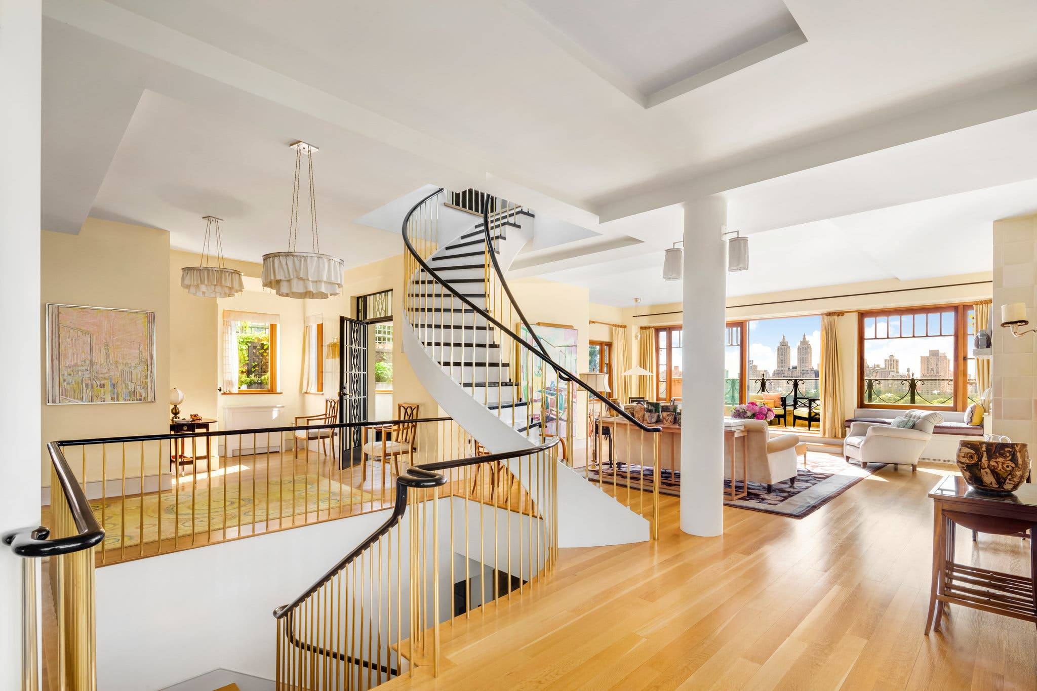 Spacious modern living room with a spiral staircase, large windows, wooden floors, and views of city skyline.