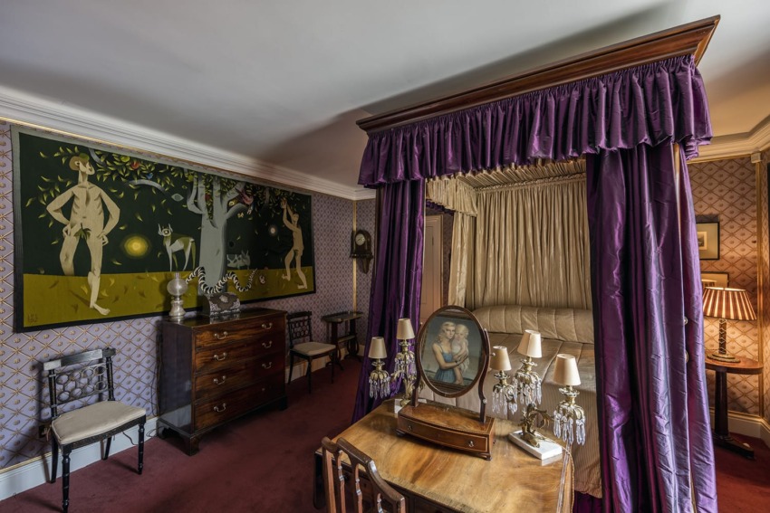 Vintage bedroom with a canopy bed, purple drapes, classic wooden furniture, and a large wall painting.