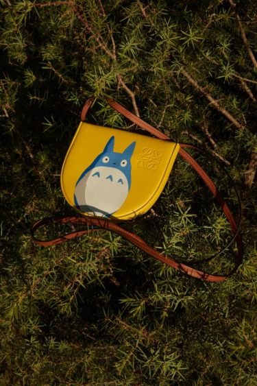 Yellow purse with blue cartoon character design on green leafy background