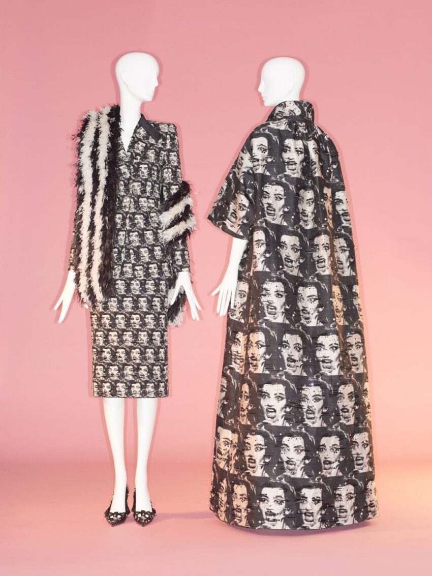 Two mannequins displaying fur-trimmed and face-patterned outfits on a pink background.