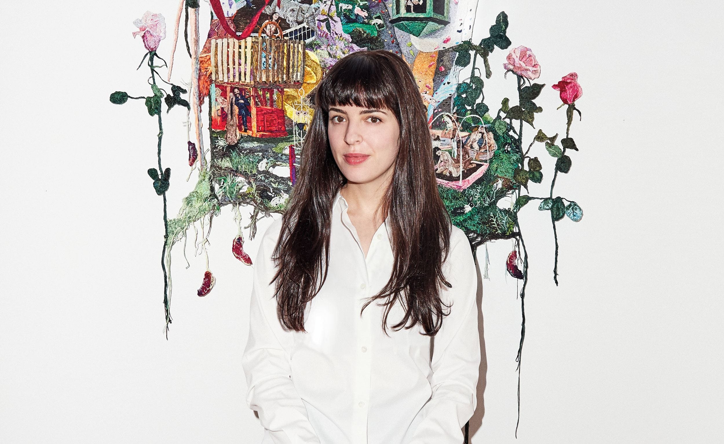 Person in a white shirt standing in front of a colorful, artistic mural with flowers and abstract elements.