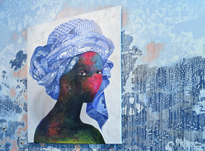 Colorful portrait of a woman with a vibrant headscarf on a textured blue patterned wall background.