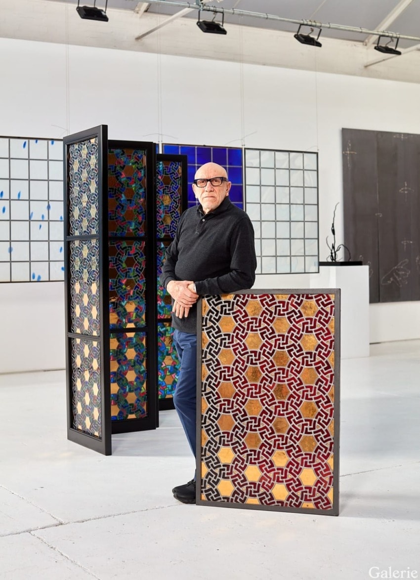 Man standing in an art gallery with colorful geometric patterns and modern artworks in the background.