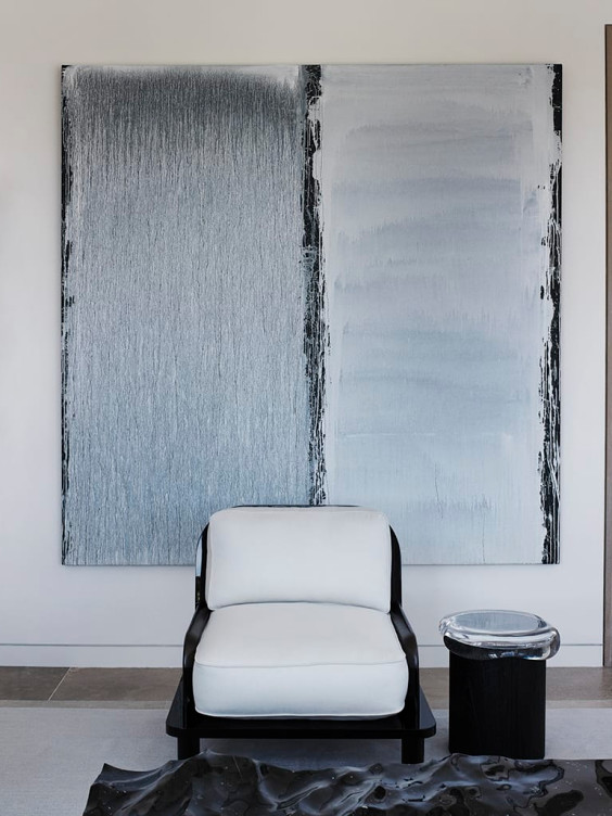 Modern art piece with monochrome vertical gradients behind a minimalist black and white chair and side table.