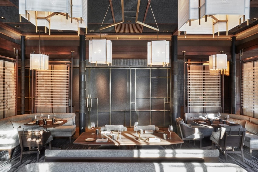 Modern restaurant interior with elegant lighting, wooden tables, and upholstered seating creating a sophisticated dining atmosphere.