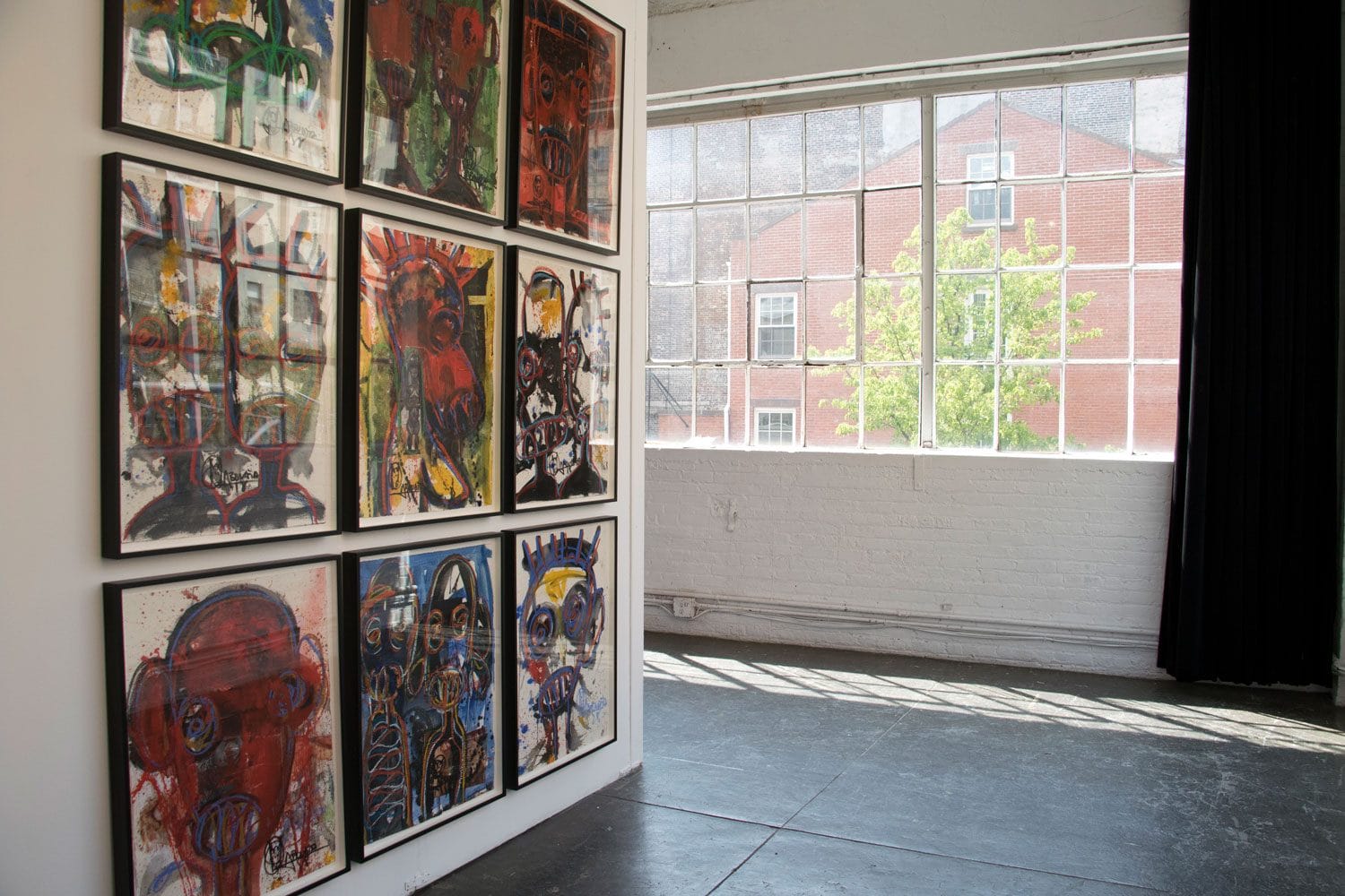 Contemporary art gallery with colorful abstract paintings on a wall, large window, and natural light illuminating the room.