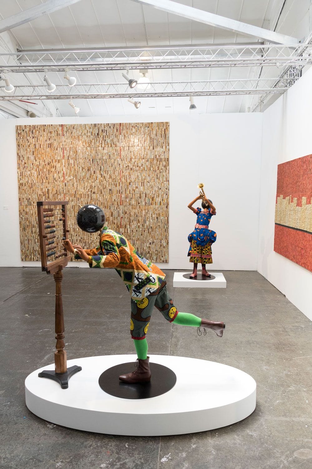 Colorful sculptures of figures interacting with objects in a modern art gallery with large abstract wall art.