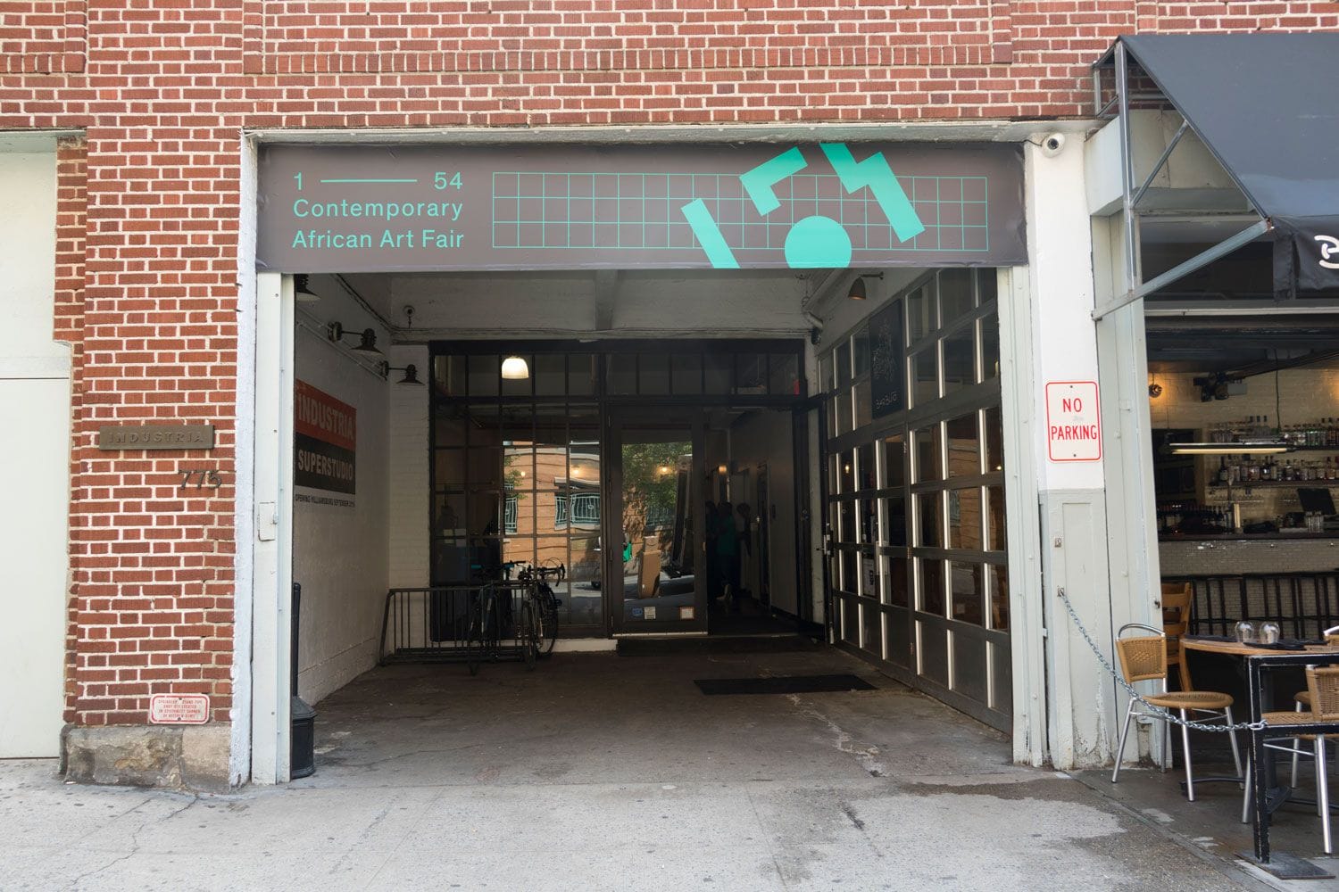Entrance to a contemporary African art fair in a brick building with a cafe on the right side.