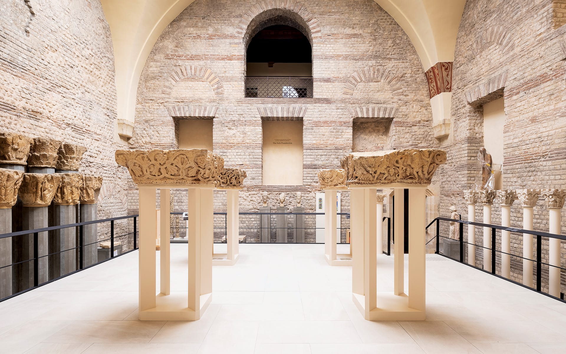Spacious interior with ancient columns and detailed stone carvings, surrounded by rustic brick walls in a historic building.