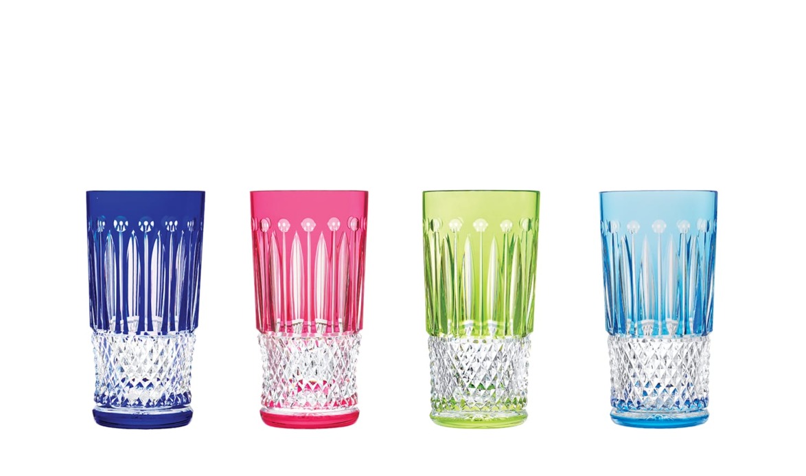 Four colorful crystal cut glasses in blue, pink, green, and light blue, aligned in a row on a white background.